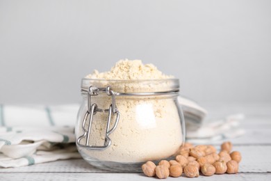 Photo of Glass jar with chickpea flour and seeds on white wooden table