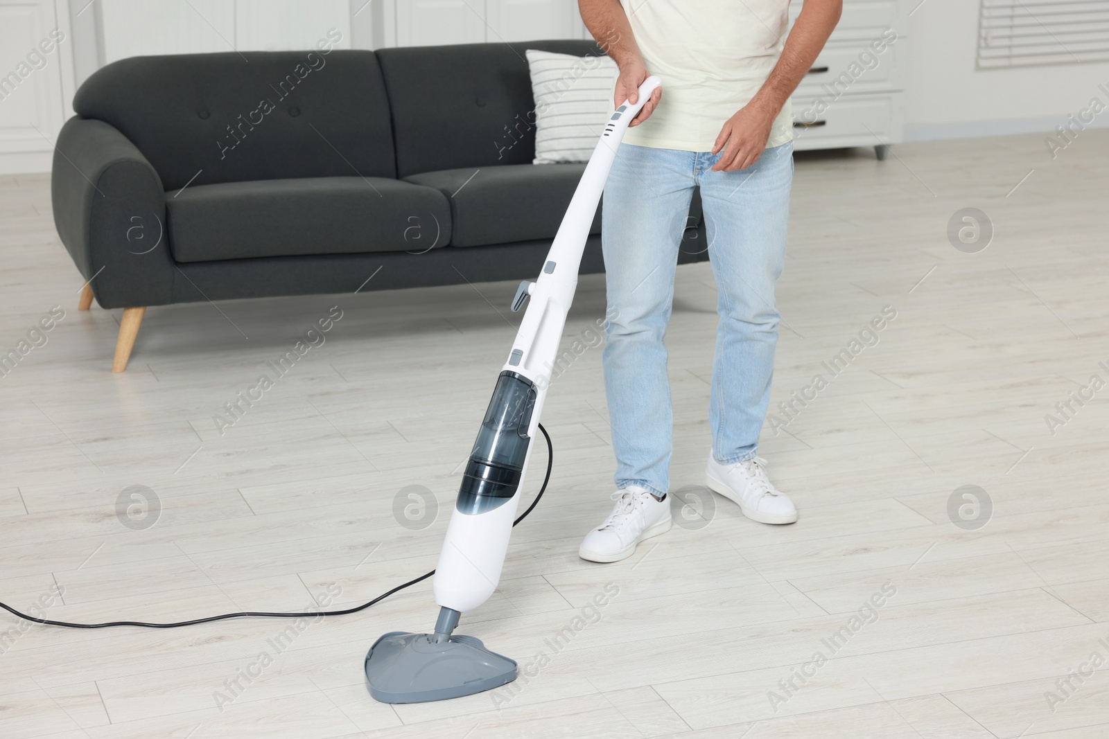 Photo of Man cleaning floor with steam mop at home, closeup