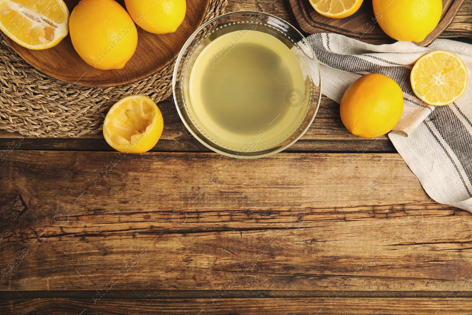 Photo of Freshly squeezed lemon juice on wooden table, flat lay. Space for text