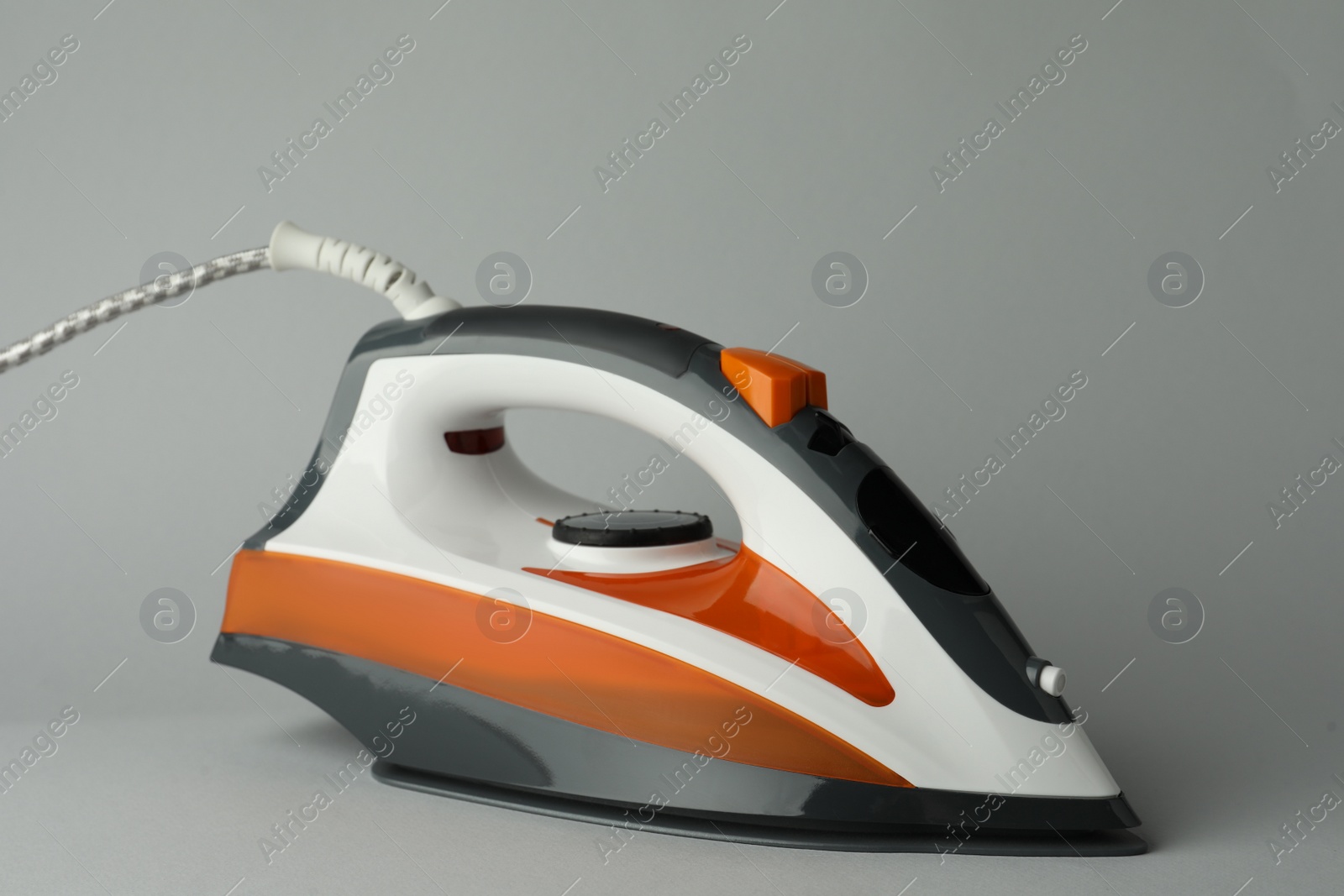 Photo of One modern iron on light grey background. Home appliance