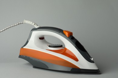 Photo of One modern iron on light grey background. Home appliance