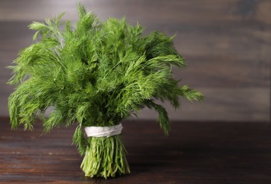 Photo of Bunch of fresh green dill on wooden table, space for text