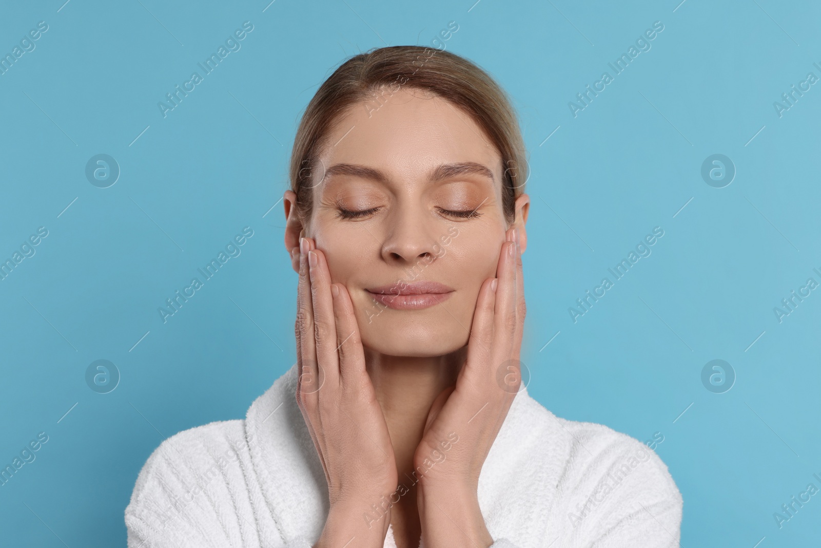 Photo of Woman massaging her face on turquoise background