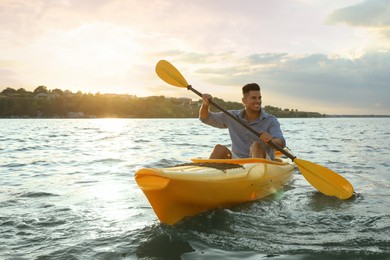 Photo of Happy man kayaking on river at sunset. Summer activity