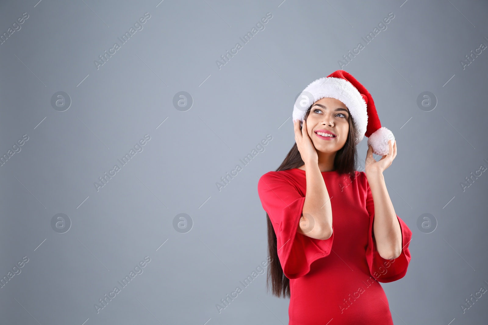 Photo of Young beautiful woman in Santa hat on grey background. Christmas celebration