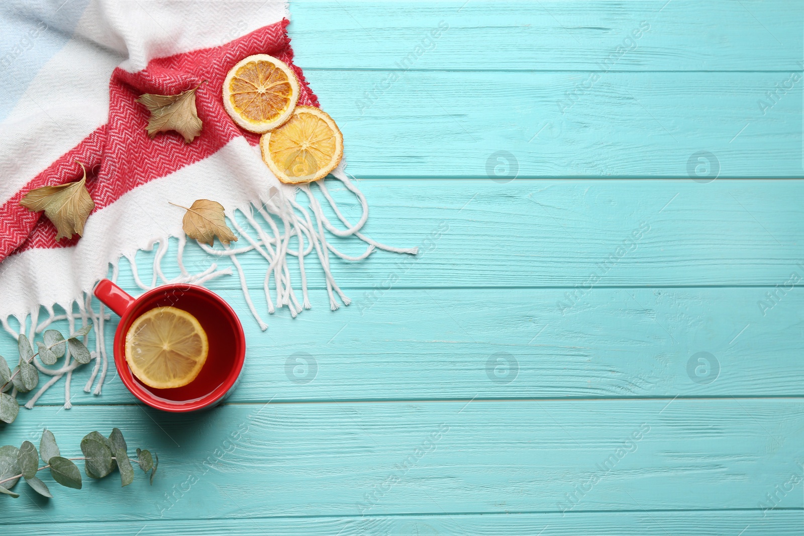 Photo of Flat lay composition with tea and warm plaid on turquoise wooden table, space for text