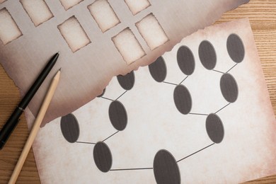 Blank family tree charts, pen and pencil on wooden table, flat lay