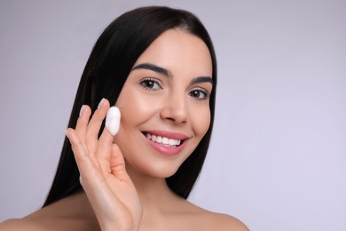 Photo of Woman using silkworm cocoon in skin care routine on light grey background. Space for text