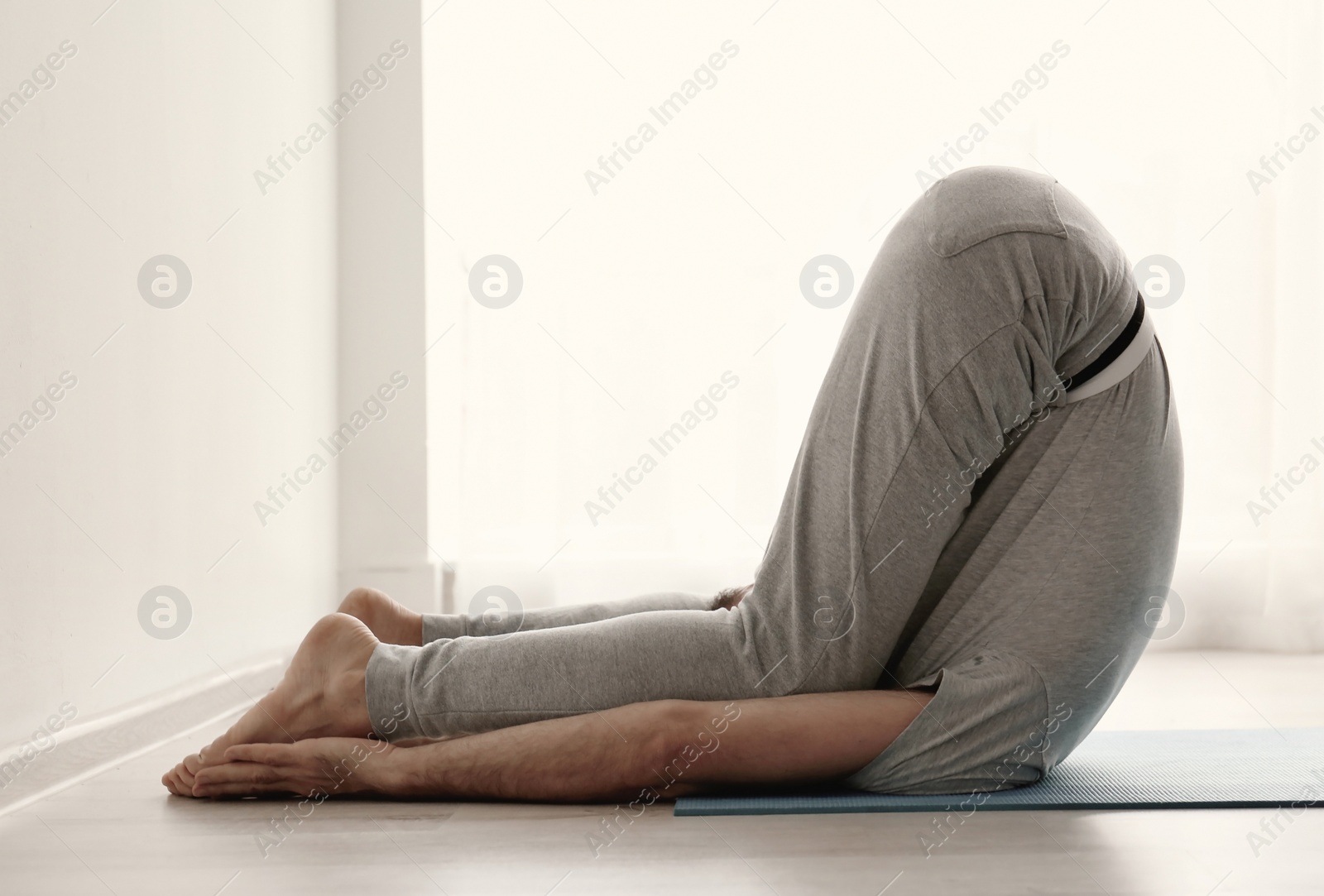 Photo of Sporty man practicing yoga indoors