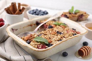 Tasty baked oatmeal with berries and almonds in baking tray on white table, closeup