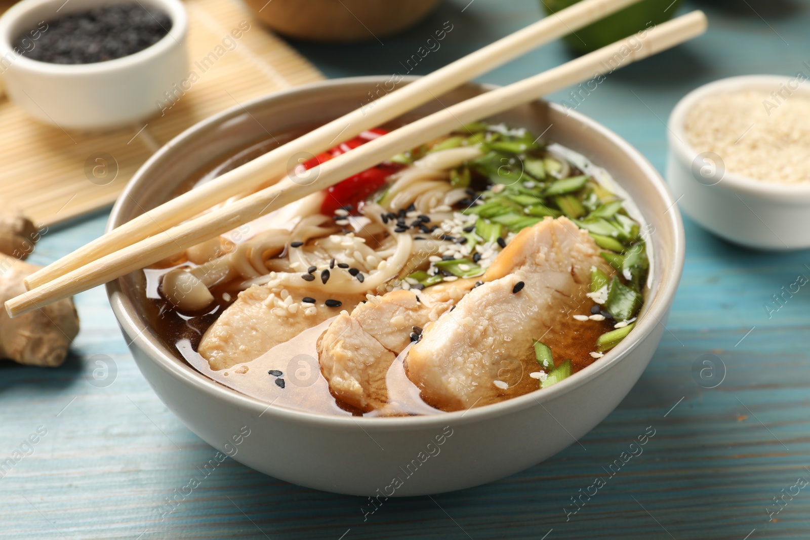 Photo of Delicious ramen with meat and ingredients on light blue wooden table, closeup. Noodle soup