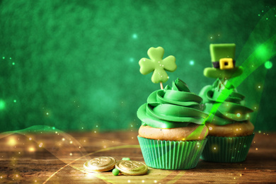 Image of Decorated cupcakes and coins on wooden table, space for text. St. Patrick's Day celebration