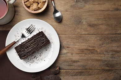 Plate with tasty Spartak cake and fork on wooden table, top view. Space for text