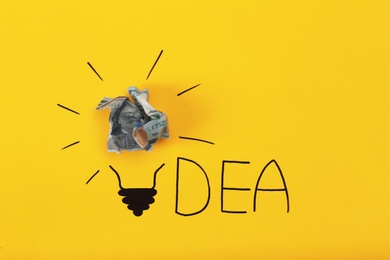 Composition with crumpled banknote, drawing of lamp bulb and word IDEA on color background. Creative concept