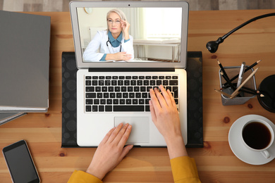 Image of Woman using laptop for online consultation with mature female doctor, top view 