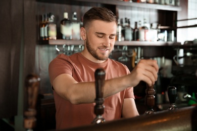 Photo of Bartender working at beer tap in pub