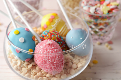 Egg shaped cake pops for Easter celebration on white wooden table, closeup