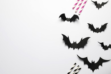 Photo of Flat lay composition with paper bats and straws on white background, space for text. Halloween celebration