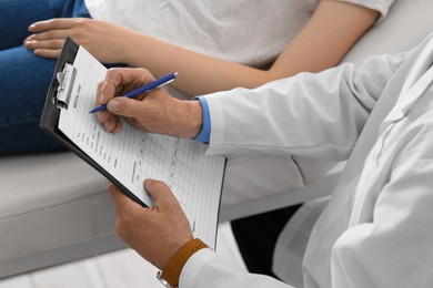 Doctor filling patient's medical card in clinic, closeup