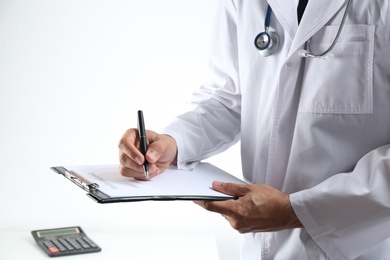 Doctor with medical insurance form indoors, closeup