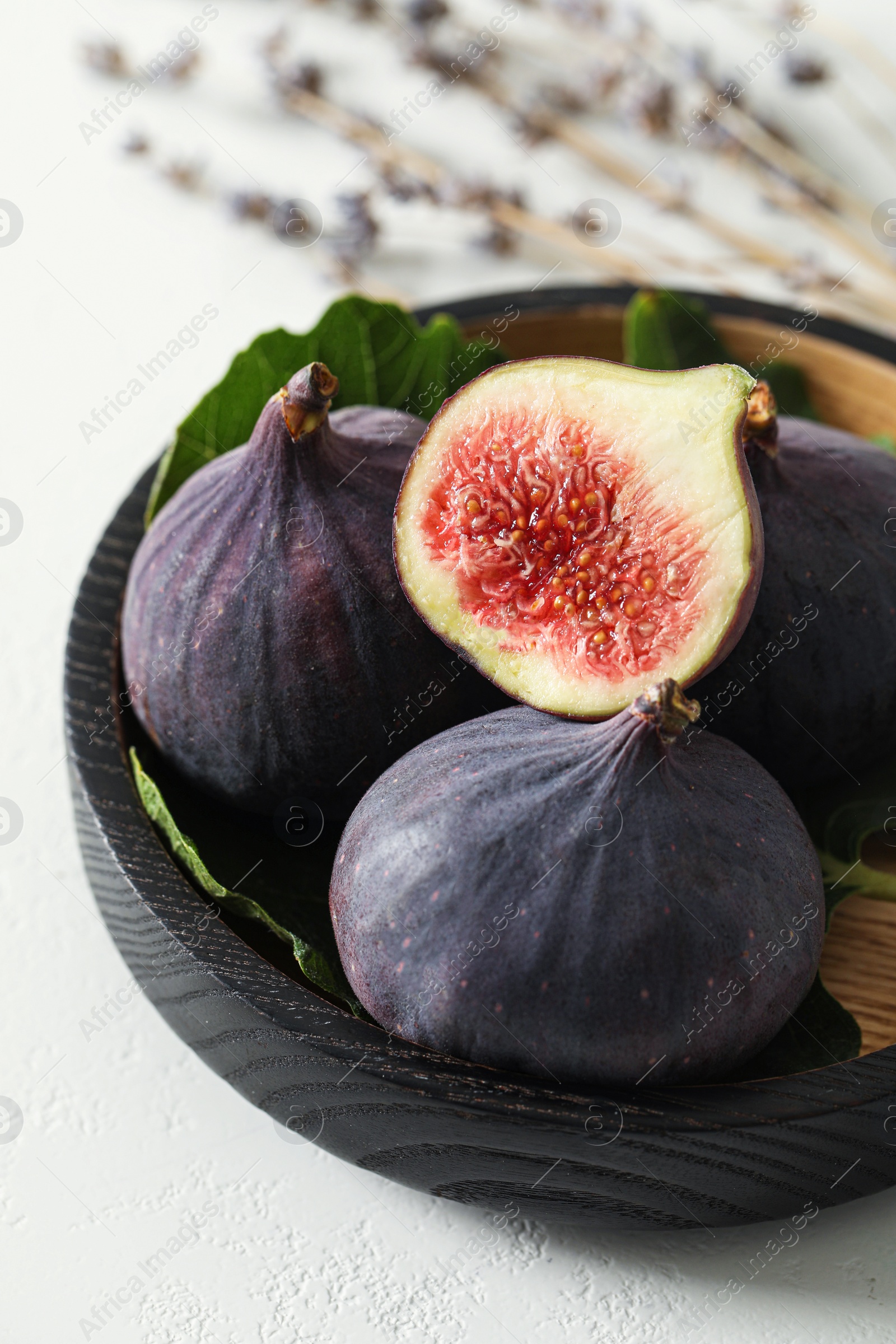 Photo of Whole and cut tasty fresh figs on white table, closeup