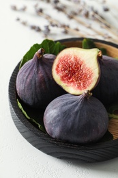 Whole and cut tasty fresh figs on white table, closeup