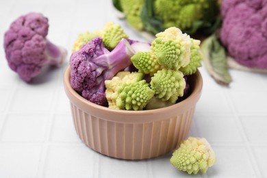 Photo of Various cauliflower cabbages on white tiled table