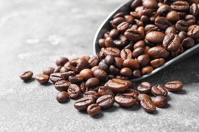 Photo of Scoop with roasted coffee beans on grey background, closeup