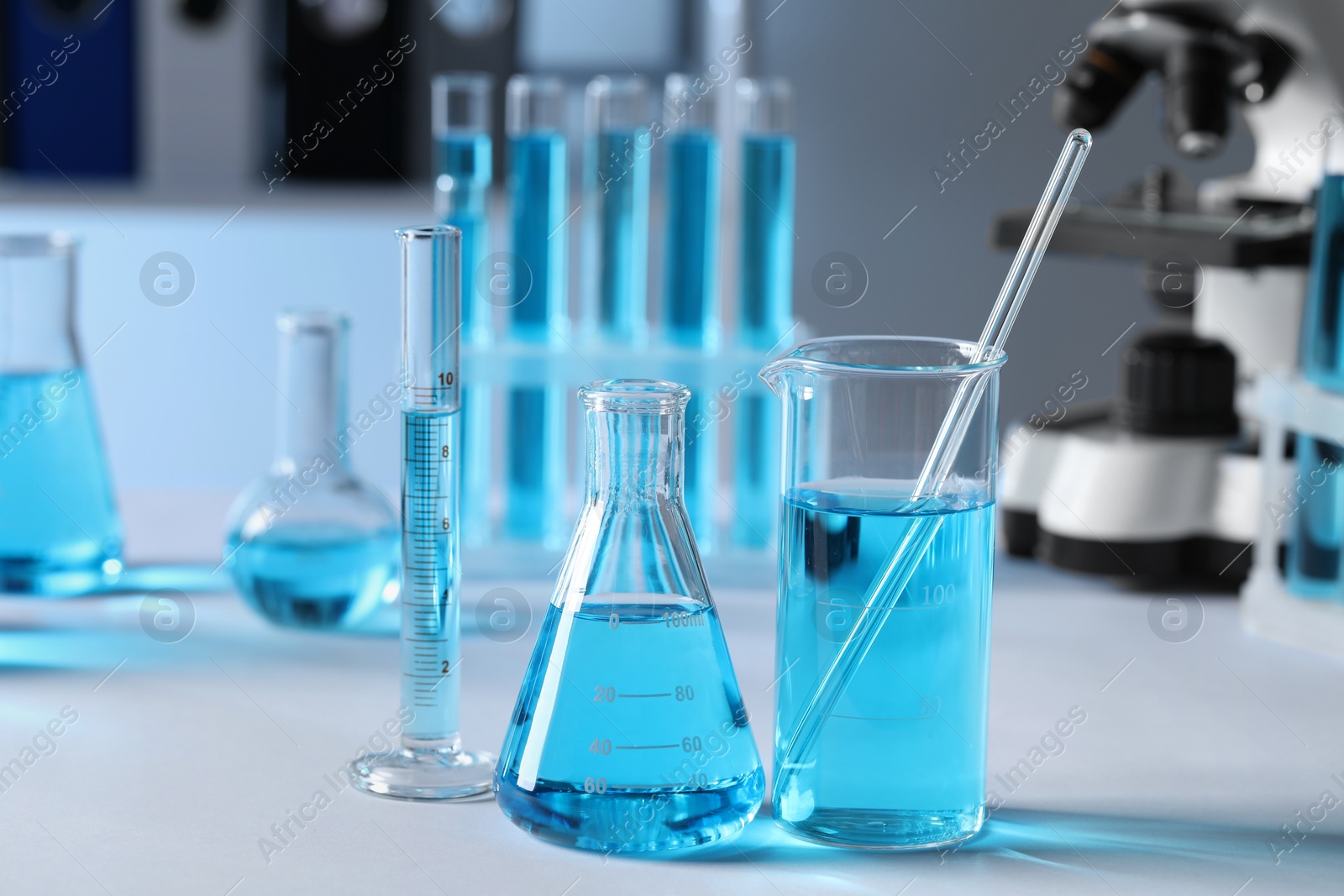 Photo of Different laboratory glassware with light blue liquid on table