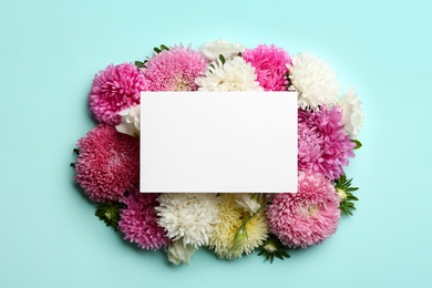 Flat lay composition with blank card and beautiful asters on light blue background, space for text. Autumn flowers