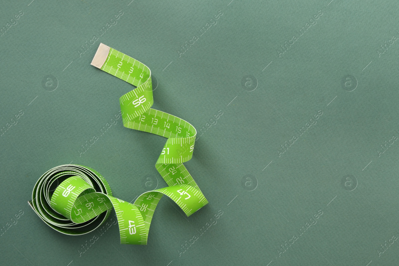 Photo of Measuring tape on green background, top view. Space for text