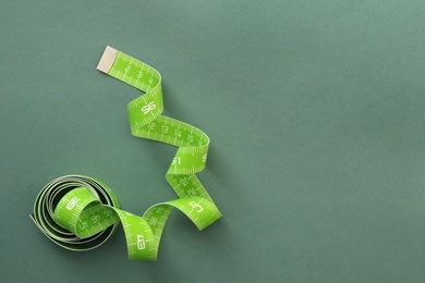 Photo of Measuring tape on green background, top view. Space for text