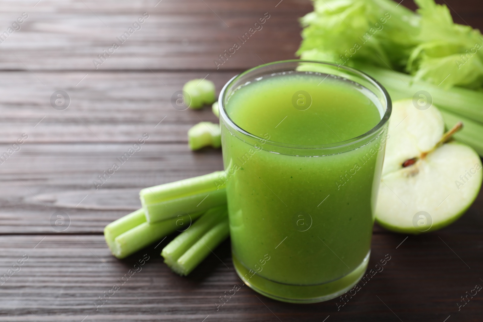 Photo of Glass of celery juice and fresh ingredients on wooden table, closeup