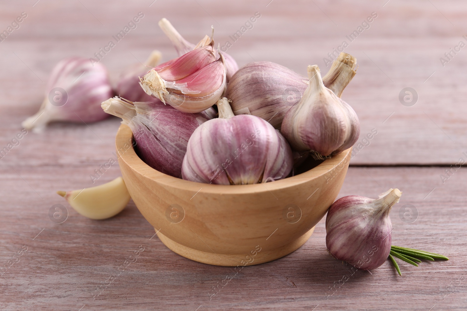 Photo of Bowl with fresh garlic on wooden table, closeup