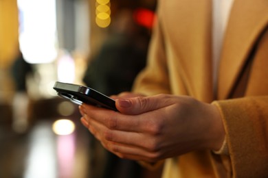 Photo of Woman with smartphone on night city street, closeup