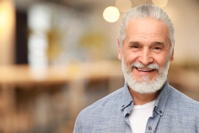 Portrait of handsome senior man in office, space for text