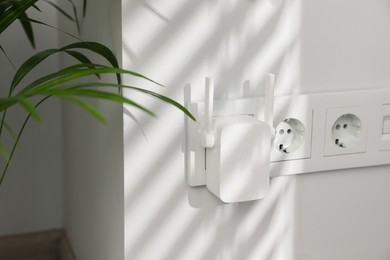 Photo of Wireless Wi-Fi repeater on white wall indoors