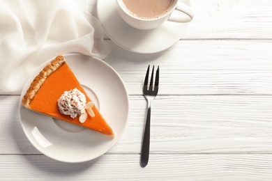 Flat lay composition with piece of fresh delicious homemade pumpkin pie and space for text on wooden background