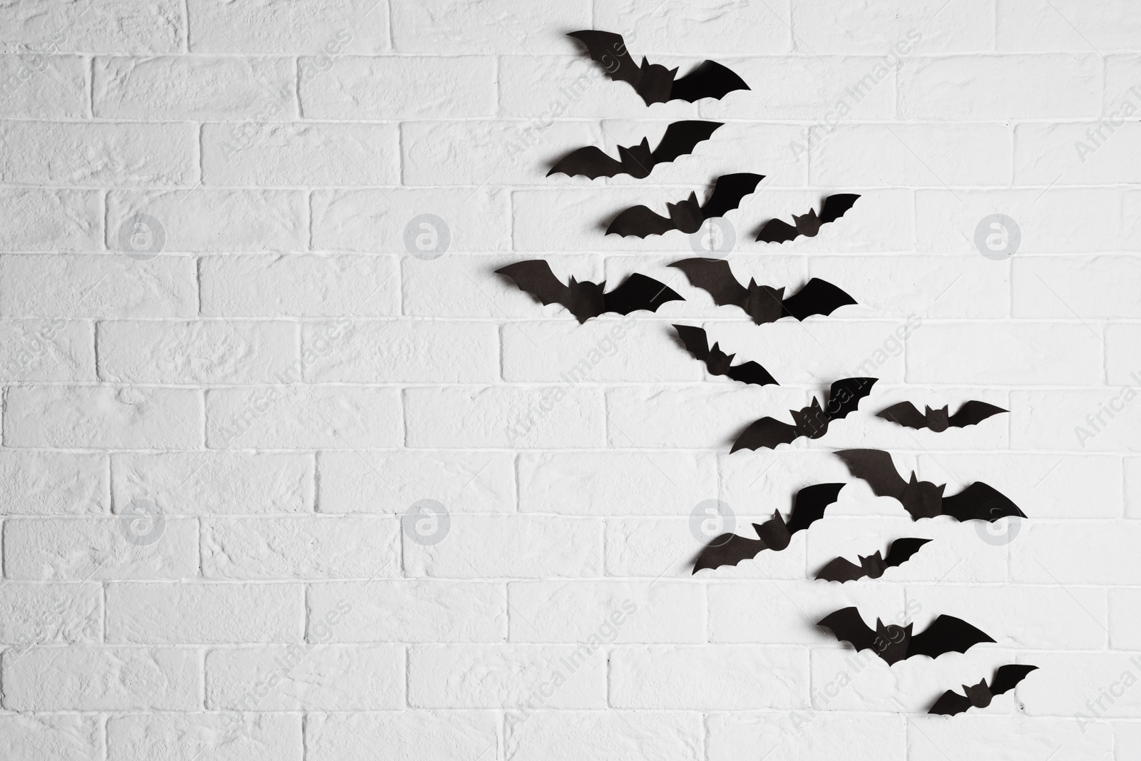 Photo of Paper bats on brick wall with space for text. Halloween decor