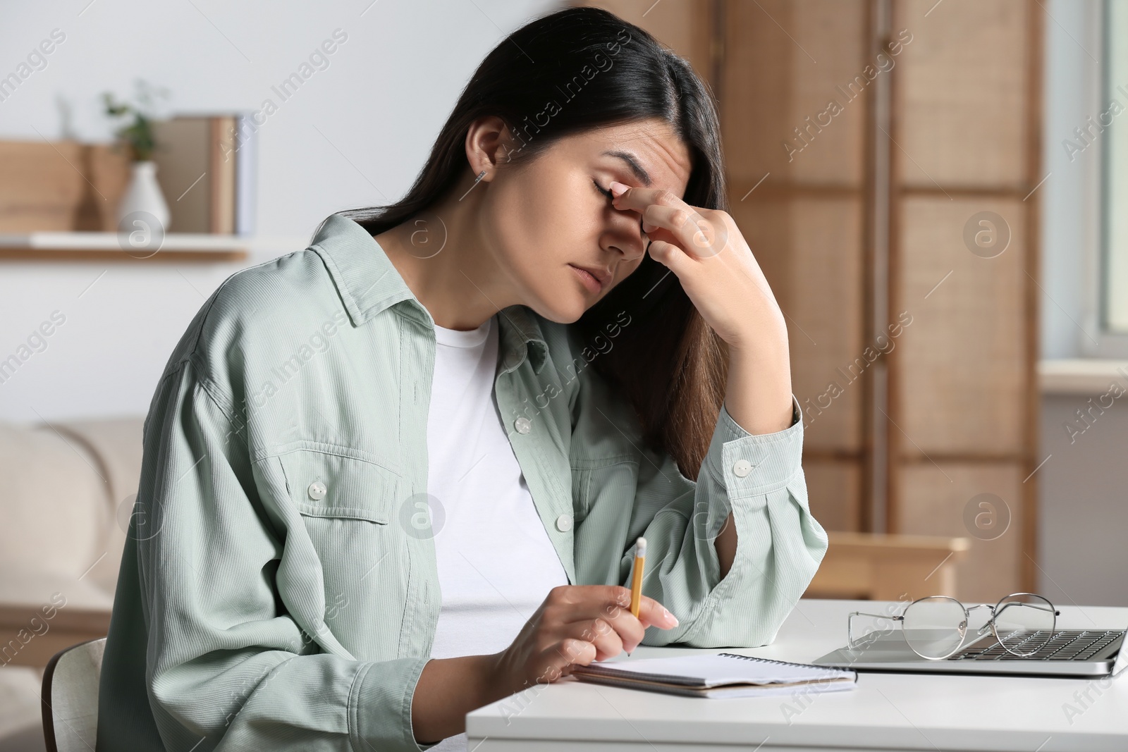 Photo of Young woman suffering from eyestrain at desk in office