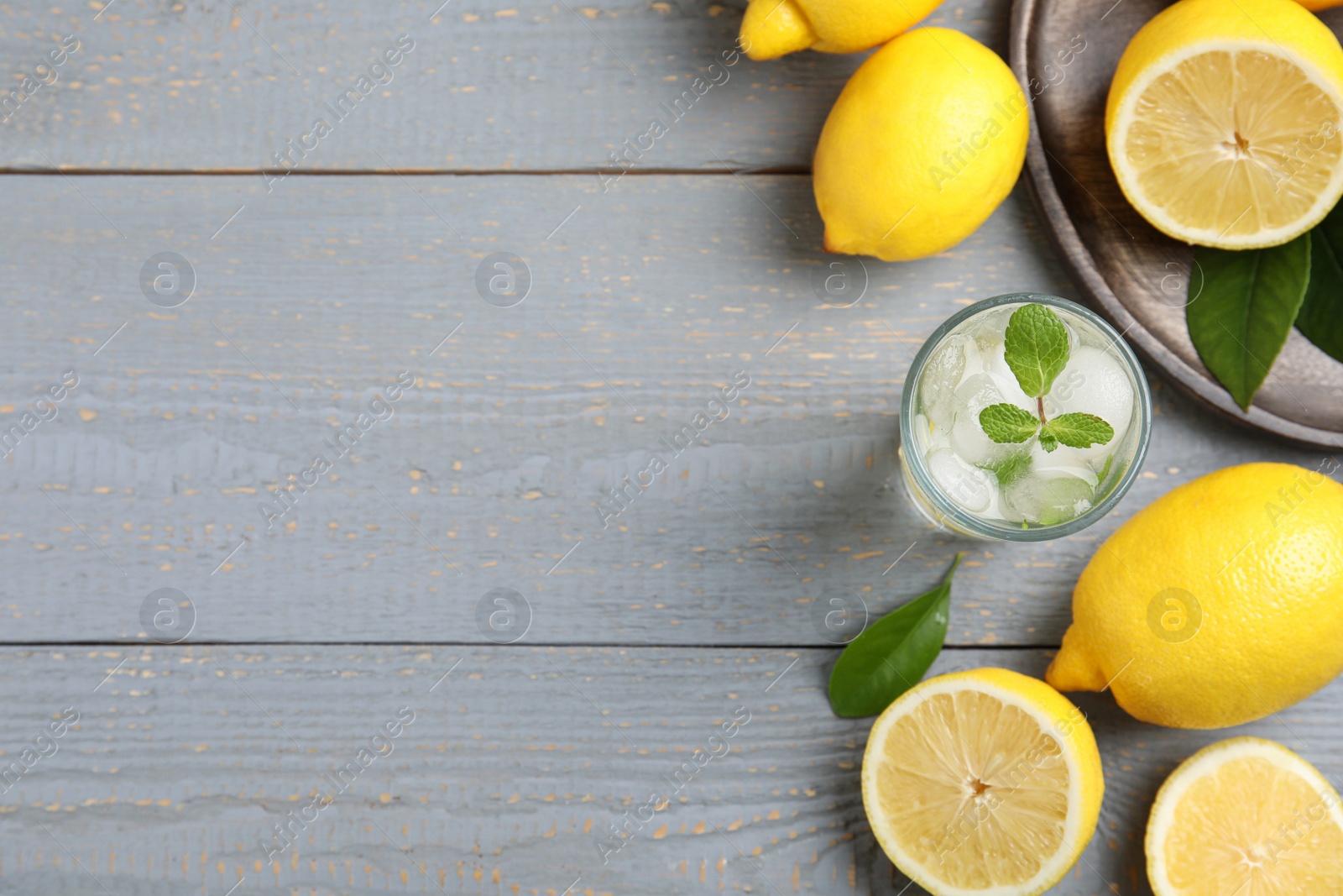 Photo of Cool freshly made lemonade and fruits on grey wooden table, flat lay. Space for text