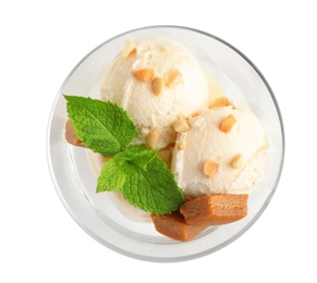 Photo of Glass bowl of ice cream with caramel candies, mint and nuts on white background, top view