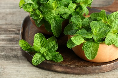Photo of Bowls with fresh green mint leaves on wooden table, closeup