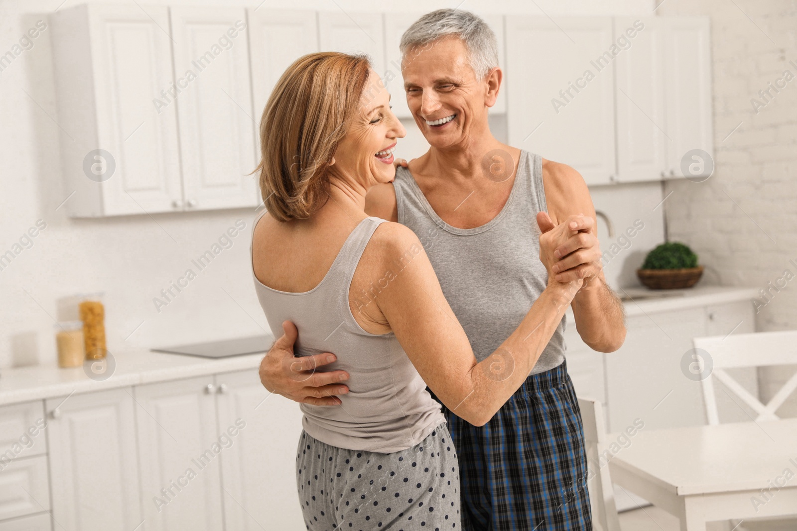 Photo of Happy senior couple dancing together in kitchen