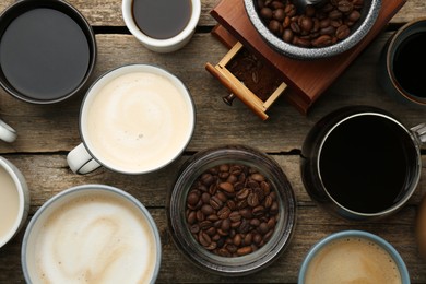 Photo of Different coffee drinks in cups, beans and manual grinder on wooden table, flat lay