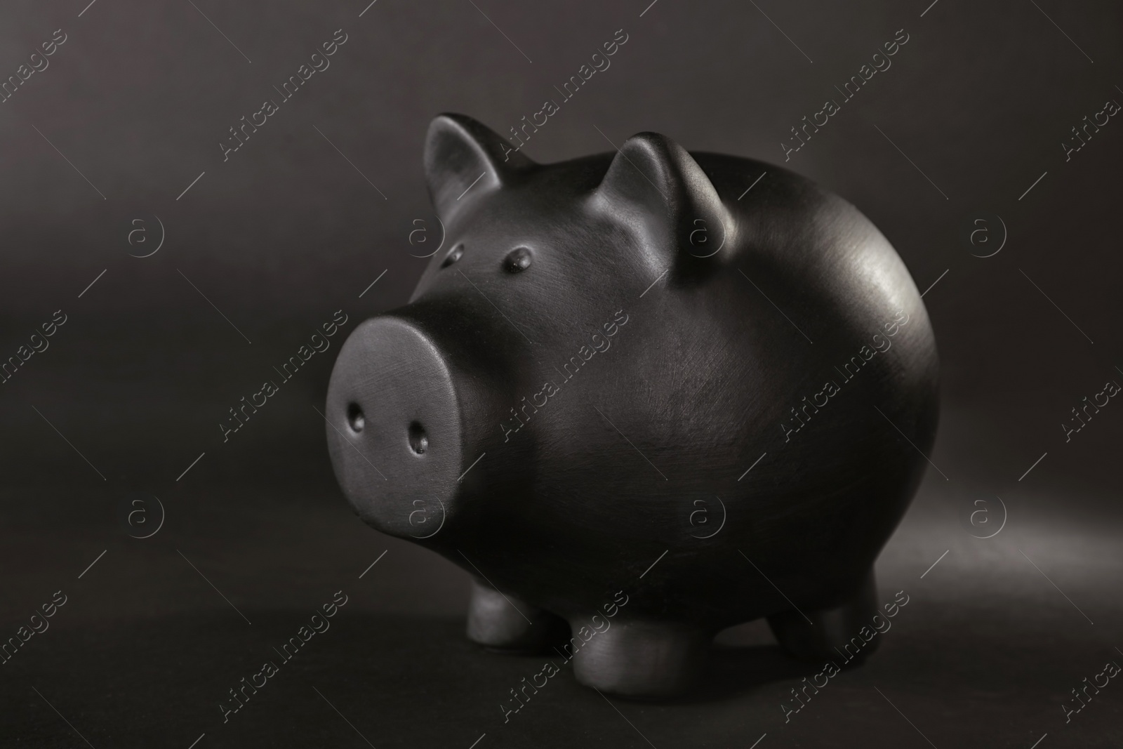 Photo of Black piggy bank on table against dark background