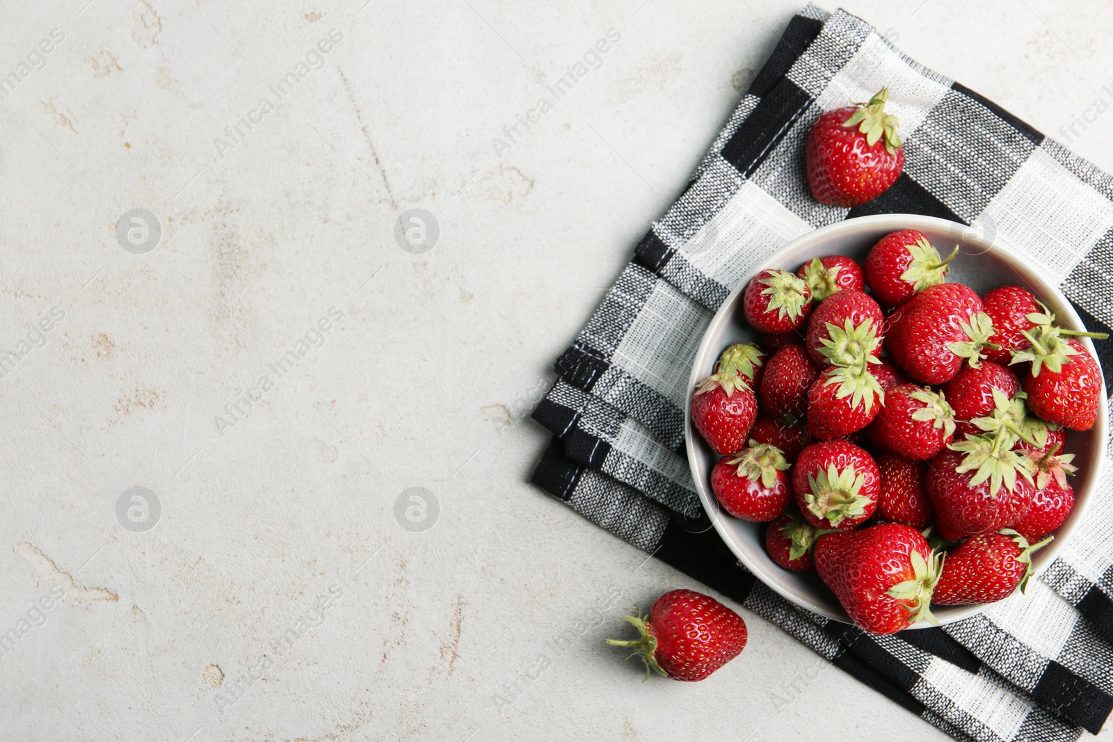 Photo of Delicious ripe strawberries in bowl on light grey table, flat lay. Space for text