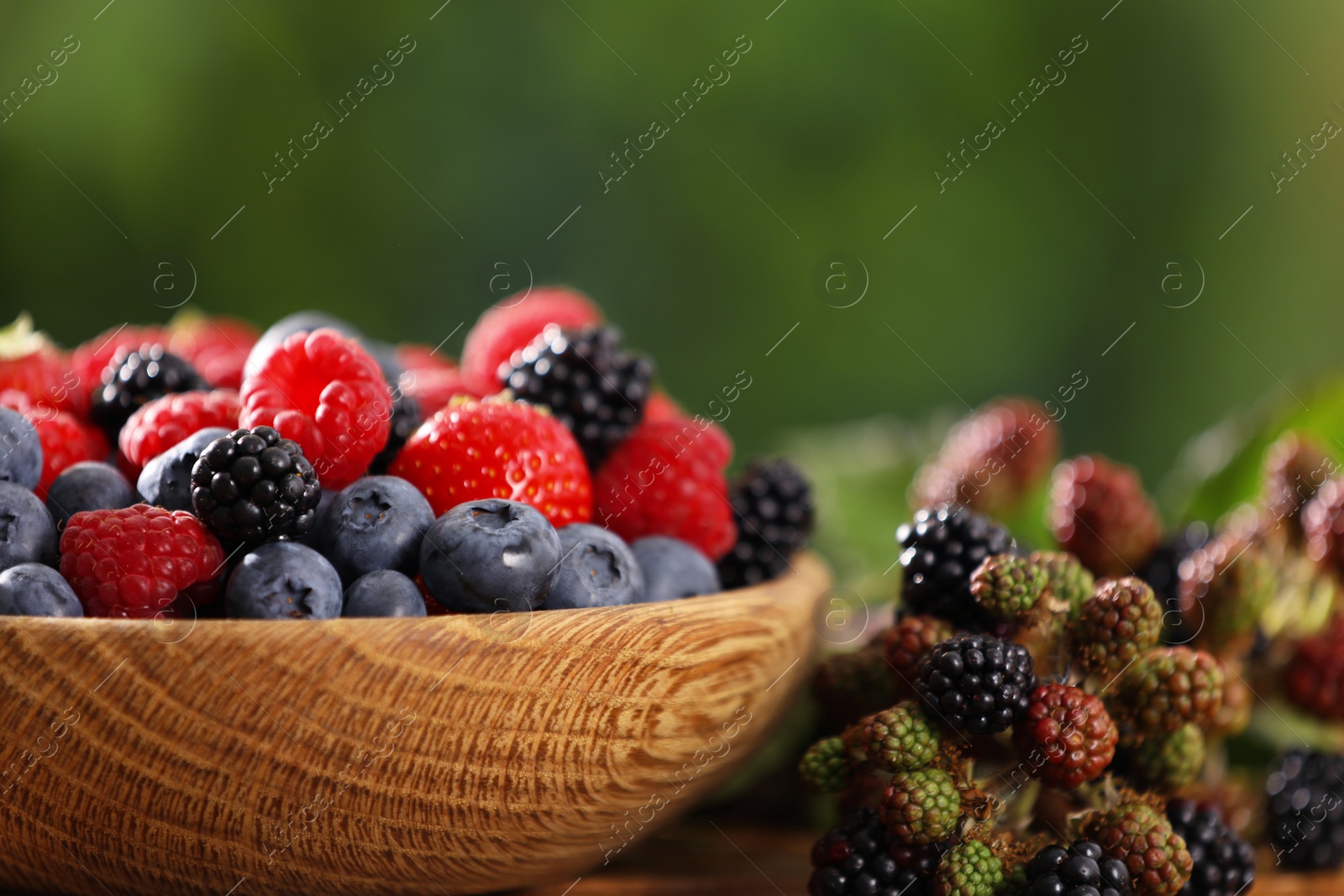 Photo of Bowl with different fresh berries on table outdoors, closeup