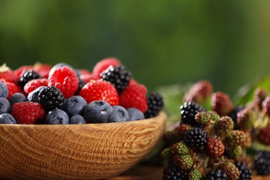 Photo of Bowl with different fresh berries on table outdoors, closeup