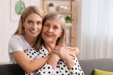 Happy mature mother and her daughter hugging at home